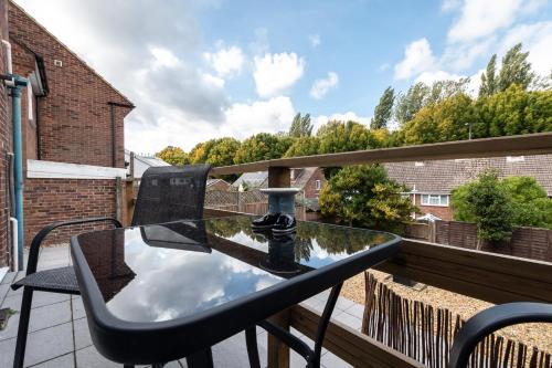 a glass table on the balcony of a house at 3 Bedrooms house ideal for long Stays! in Southampton