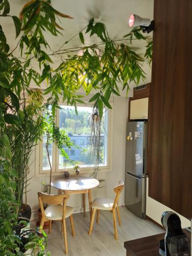 uma cozinha com mesa, cadeiras e plantas em Paradise apartment em Vantaa