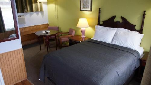 Habitación de hotel con cama, mesa y silla en Robyn's Motel en Peterborough
