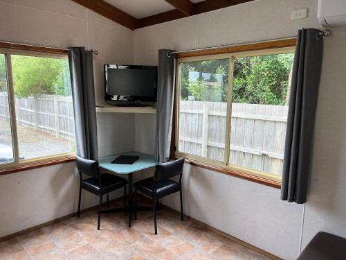 a room with a table and a tv and two windows at Lakes Main Holiday Park in Lakes Entrance