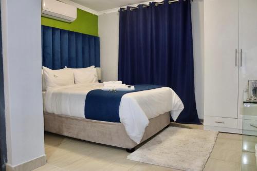 1 dormitorio con 1 cama grande y cortinas azules en Uzuri Lifestyle en Port St Johns