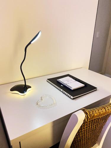 un escritorio con una lámpara y un libro. en São Paulo Moema Times Square - Suite LUXO en São Paulo