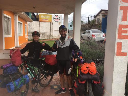 duas pessoas de pé com as suas bicicletas numa bomba de gasolina em Hotel Pousaria em Guarapuava