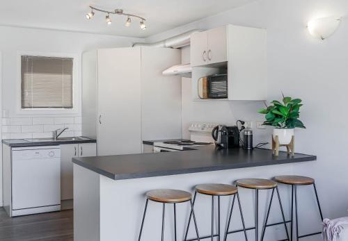 a kitchen with white cabinets and a counter with stools at Amazing Views in Downtown Queenstown in Queenstown