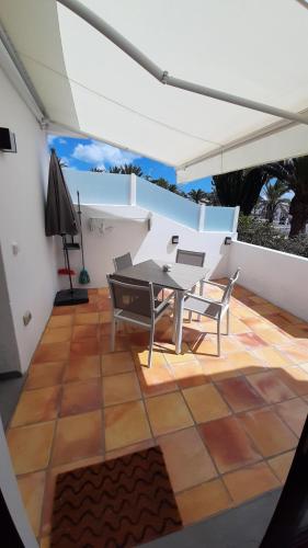 patio ze stołem i krzesłami na białej ścianie w obiekcie El Gueco Holiday Apartment w Costa Teguise