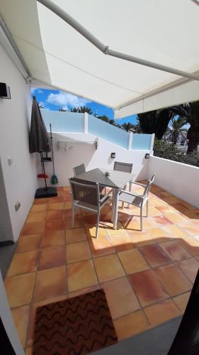 un patio con tavolo e sedie su una parete bianca di El Gueco Holiday Apartment a Costa Teguise