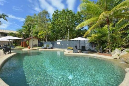 a swimming pool with turquoise water and palm trees at Wanderer in Port Douglas