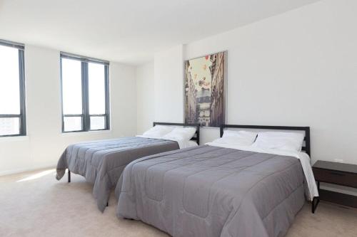 two beds in a white room with windows at Nice 2BR Pentagon City Apartment in Arlington