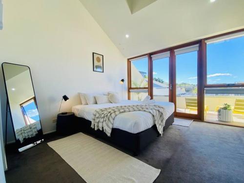 a bedroom with a large bed and large windows at Poolside Apartment In Central Byron in Byron Bay