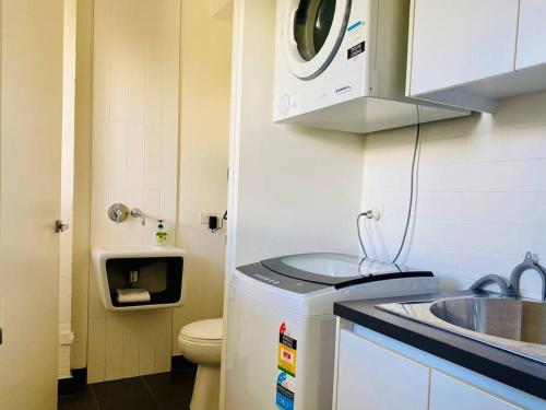 a small kitchen with a sink and a washing machine at Poolside Apartment In Central Byron in Byron Bay