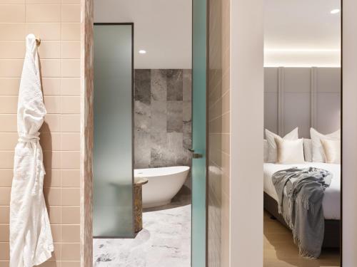 a bathroom with a bed and a tub in a room at The Porter House Hotel Sydney - MGallery in Sydney