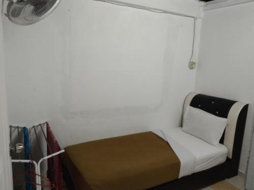 a small bedroom with a bed and a fan at khairul homestay taman tengiri seberang jaya in Kampong Telok