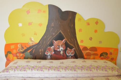 a bed with a painting of three foxes in a tree at Agriturismo Prato degli Angeli in Sassoleone