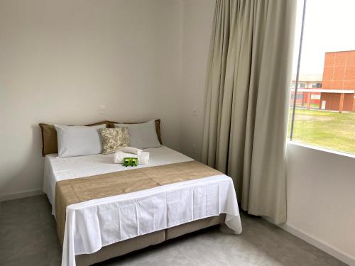 um pequeno quarto com uma cama e uma janela em Pousada Divino Oleiro - Gov. Celso Ramos em Governador Celso Ramos