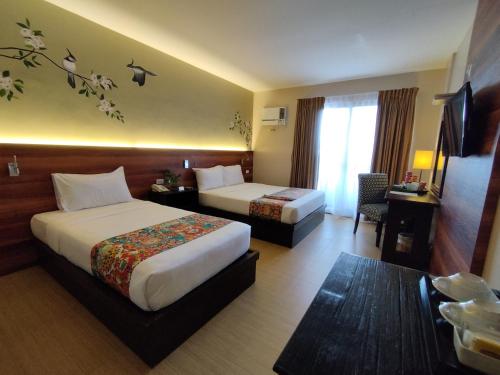 a hotel room with two beds and a table at Hotel Kimberly Tagaytay in Tagaytay