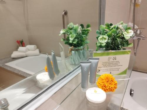 a bathroom counter with flowers in vases and a mirror at Hotel Kimberly Tagaytay in Tagaytay