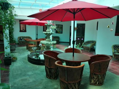 a patio with tables and chairs with a fountain and red umbrellas at CASA GRANDE HERMOSA in Erongarícuaro