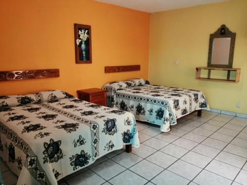 two beds in a room with orange walls at CASA GRANDE HERMOSA in Erongarícuaro