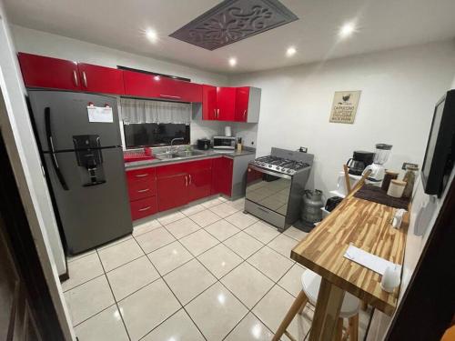 uma cozinha com armários vermelhos e um frigorífico preto em Elegante Casa de 4 Habitaciones a Solo 15 Minutos del Corazón de la Ciudad em San José