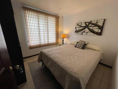 um quarto com uma cama, um candeeiro e uma janela em Elegante Casa de 4 Habitaciones a Solo 15 Minutos del Corazón de la Ciudad em San José