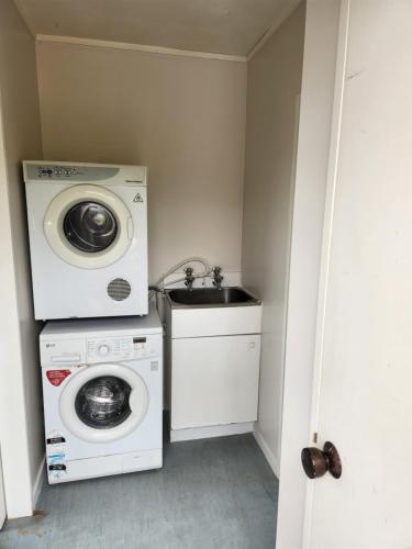 een wasruimte met een wasmachine en een wastafel bij Whalers retreat in Pukenui