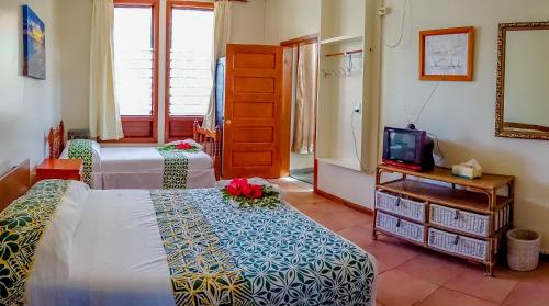 a hotel room with two beds and a tv at Lynn's Getaway Hotel in Apia