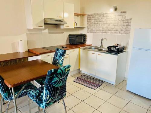 eine Küche mit einem Tisch, einer Spüle und einem Kühlschrank in der Unterkunft Studio Papeete Lodge - Kaoha Nui in Papeete