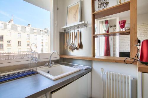 eine Küche mit einem Waschbecken und einem Fenster in der Unterkunft Studio Republique Pierre Levé in Paris