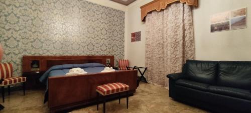 una camera da letto con un letto, un divano e una sedia di Giardinetto Papale, centralissimo a Caltagirone