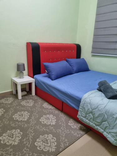 a bedroom with a bed with blue pillows and a table at D’Lestari Homestay in Seri Kembangan