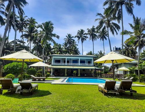 a resort with a swimming pool and chairs and umbrellas at Crystal Villa in Weligama