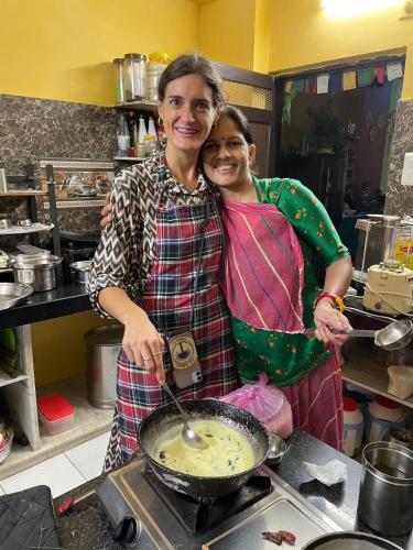 two women standing in a kitchen preparing food at Black Pepper Home Stay in Udaipur