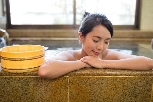 a woman laying in a bath tub with a yellow bowl at Yawarano-yu MARUYA For women only in Ise