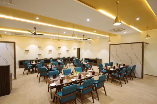 a banquet hall with tables and blue chairs at Jagira Ananta Elite , Sasan Gir in Chitrod