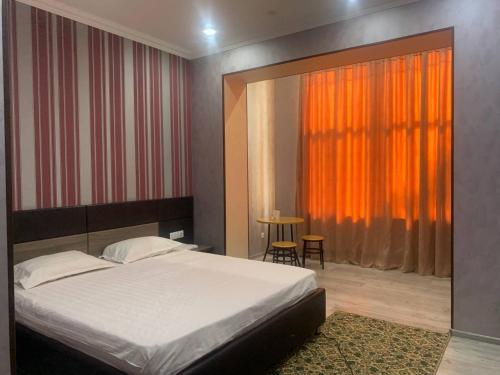 a bedroom with a bed and a large window at Armon Apart Hotel in Khujand