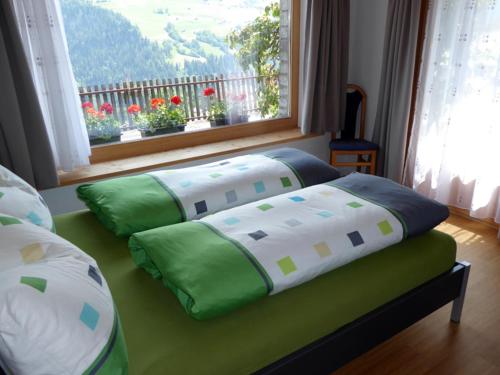 a bed with green and white pillows and a window at Dado Casanova in Cumbels