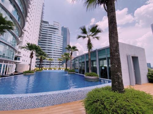 uma grande piscina com palmeiras e edifícios em Vortex Suites KLCC By Welt em Kuala Lumpur