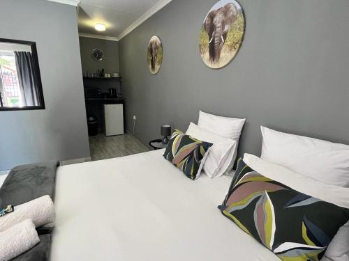 a bedroom with a large white bed with two pillows at Kudu Cottages in Kathu