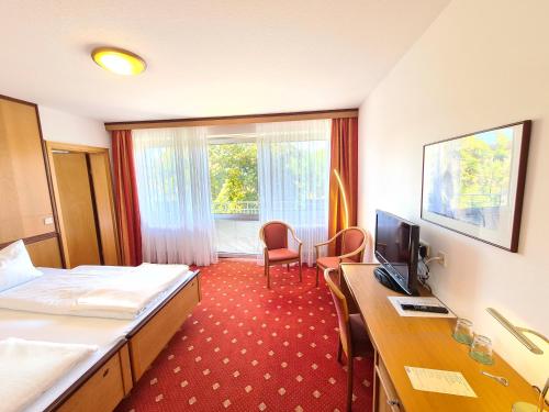 a hotel room with a bed and a desk at Thermenhotel Tannenhof - Ihr Wohlfühl-Hotel in Bad Füssing
