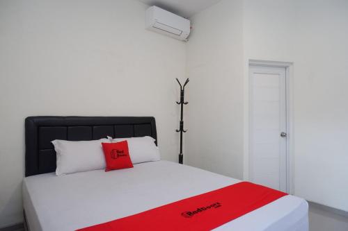 a bed with a red pillow on top of it at RedDoorz Syariah near RS Soeradji Pemuda Klaten in Klaten