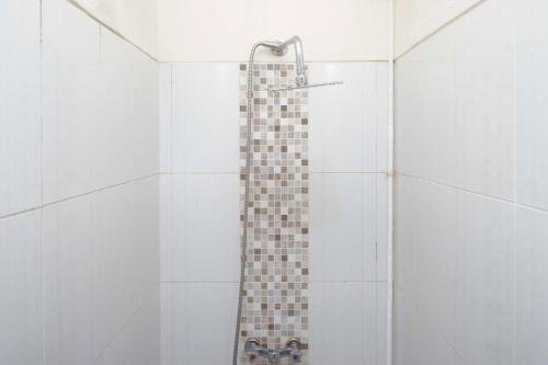 a shower with a tile wall and a shower head at RedDoorz Syariah near RS Soeradji Pemuda Klaten in Klaten