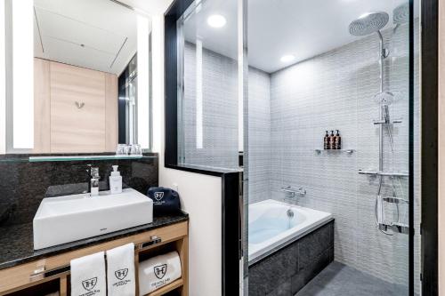 a bathroom with a sink and a tub and a shower at The Royal Park Canvas - Osaka Kitahama in Osaka