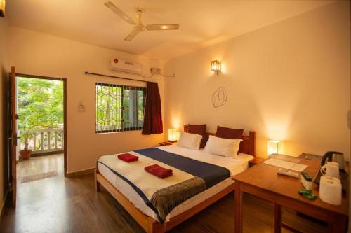 a bedroom with a bed and a table and a window at Crystall Goa Palolem in Palolem