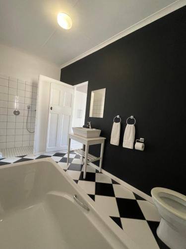 a bathroom with a white tub and a black wall at Back Home Bed and Breakfast in Graaff-Reinet