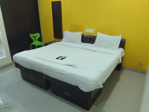バンガロールにあるHotel Amster Innの緑の椅子が備わる客室の大型ベッド1台分です。