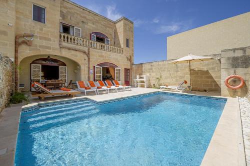 a swimming pool in front of a house at Narcisa Holiday Home in Nadur