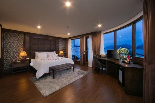 a bedroom with a bed and a desk and windows at Mon Cheri Cruises in Ha Long