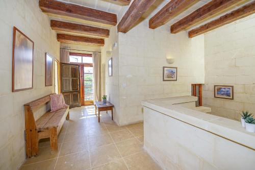 a bathroom with a tub and a bench in a room at Razzett Luna Holiday Home in Xagħra