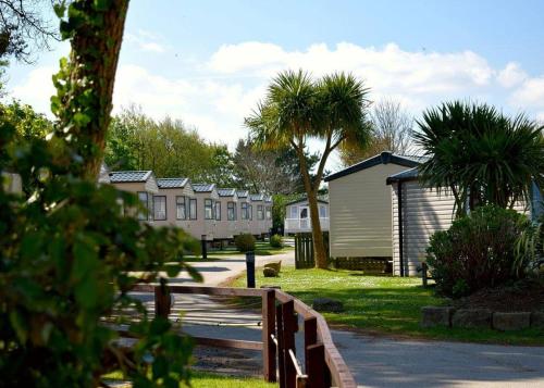 a row of houses with a fence and palm trees at Monkey Tree Holiday Park in Newquay