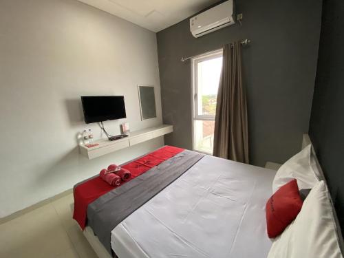 1 dormitorio con 1 cama blanca grande con almohadas rojas en RedDoorz near RSUD Margono Purwokerto 3, en Purwokerto